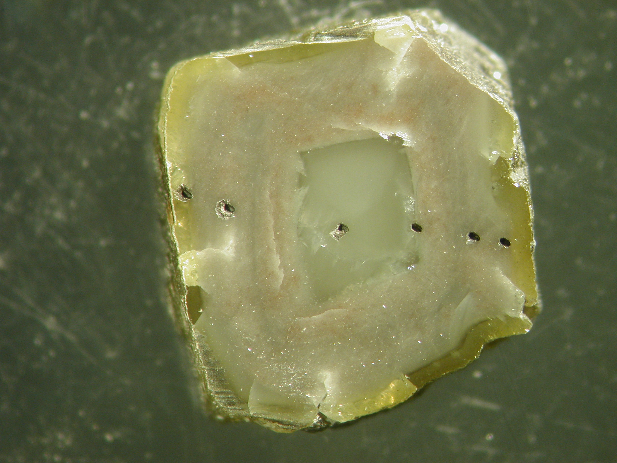 The dark dots on this diamond come from laser ablation pits used to take microscopic samples for chemical analysis.